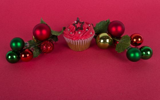 Christmas cupcake and tree ornaments on red background