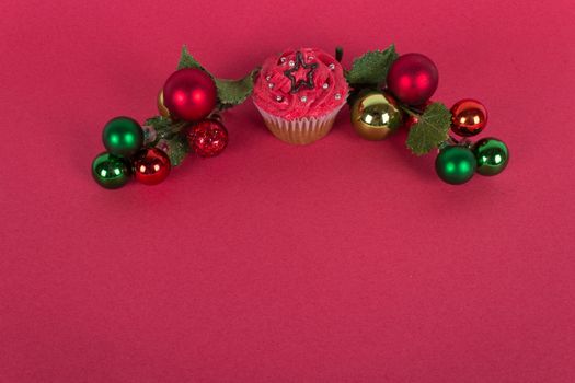 Christmas cupcake and tree ornaments on red background