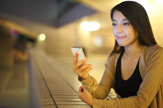 woman using smartphone in city at night