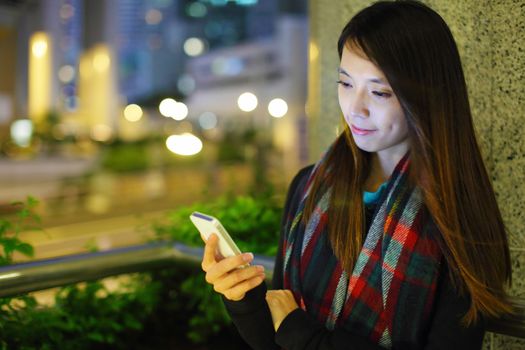 Woman using smartphone in city at night