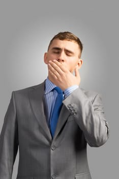 Portrait of a tired young businessman yawning behind her hand