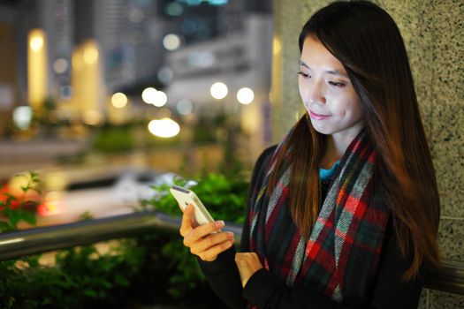 Woman using smartphone in city at night