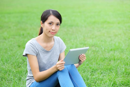 Woman sitting on grass with tablet computer