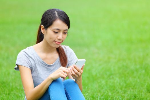 Woman sitting on grass with smartphone