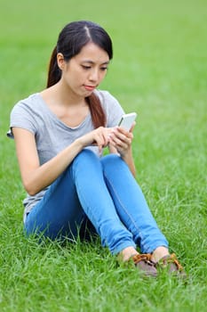 Woman sitting on grass with smartphone