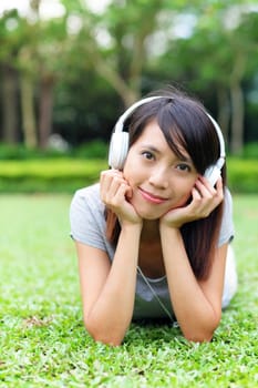 Asian woman listen to song lying on grass