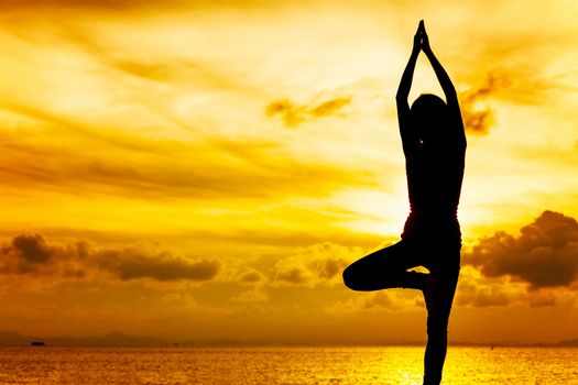 Woman doing yoga at sunset time