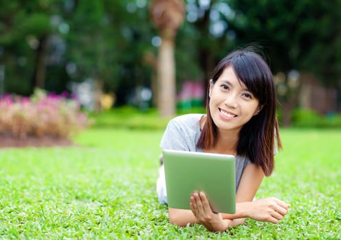 Woman lying on grass with tablet computer