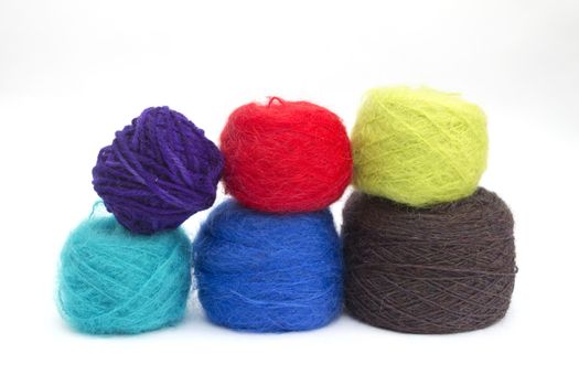 Various balls of coloured wools on a white background