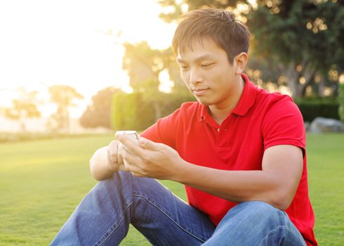 man sits on grass and use mobile phone