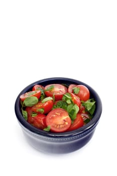 Tomatoes and basil in black bowl on a white background