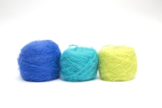 Various balls of coloured wools on a white background
