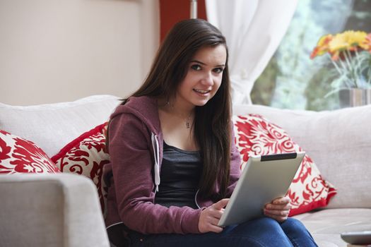 Teenage girl using a tablet pc while sitting at home