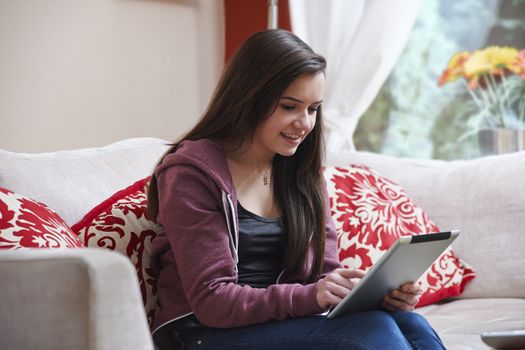 Teenage girl using a tablet pc while sitting at home