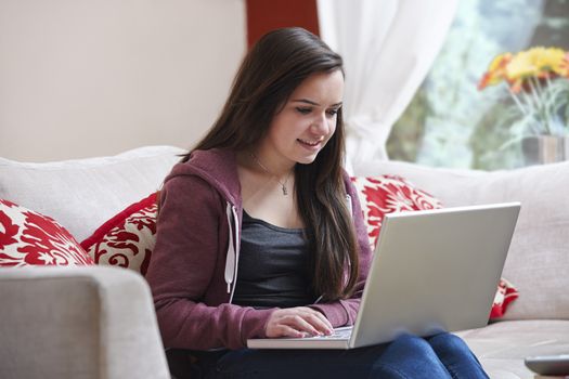 Teenage girl using a laptop computer while sitting at home