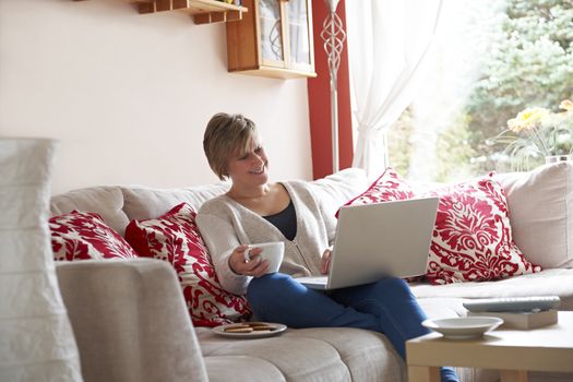 Mother enjoying surfing on the net while relaxing at home with coffee