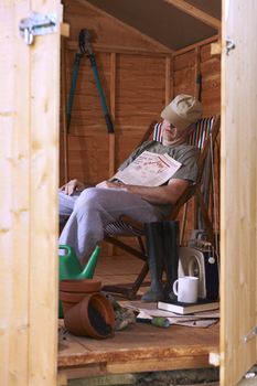 Man sitting in deckchair falling asleep in the shed
