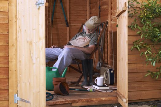 Man sitting in deckchair falling asleep in the shed