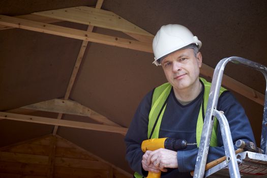 Portrait of builder standing by ladder with hard hat and high visibility jacket