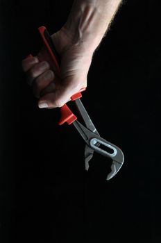 Pliers and a Hand on a Black Background