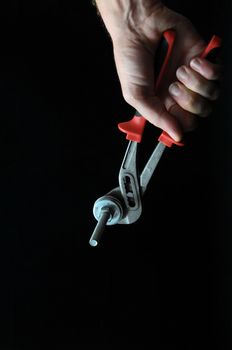 Pliers and a Hand on a Black Background
