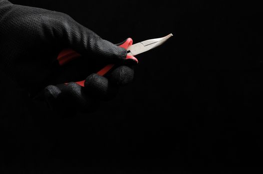 Pliers and a Hand on a Black Background