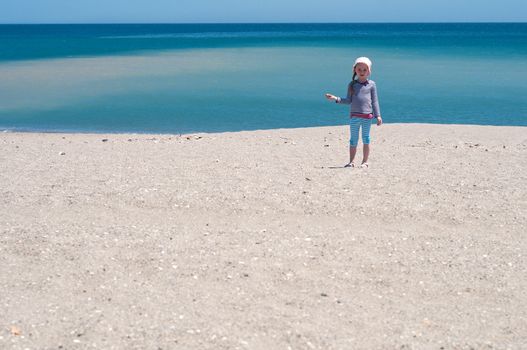 Little girl playing on the beach, coast and blue sea