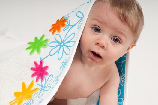 Baby boy in white towel with multicolored flowers