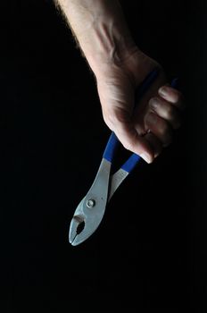 Pliers and a Hand on a Black Background