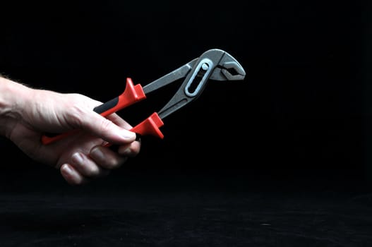 Pliers and a Hand on a Black Background