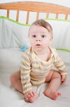 Baby boy in striprd clothes sitting in cradle