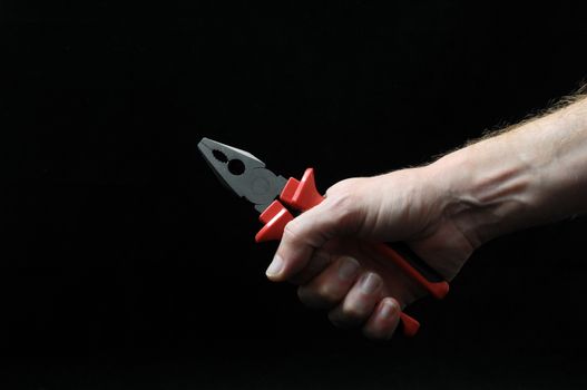 Pliers and a Hand on a Black Background