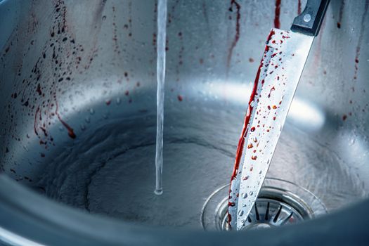 Cleaning bloody knife in kitchen sink, Halloween or crime scene 