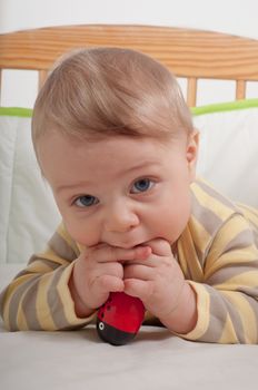 Baby boy in cradle playing with toy