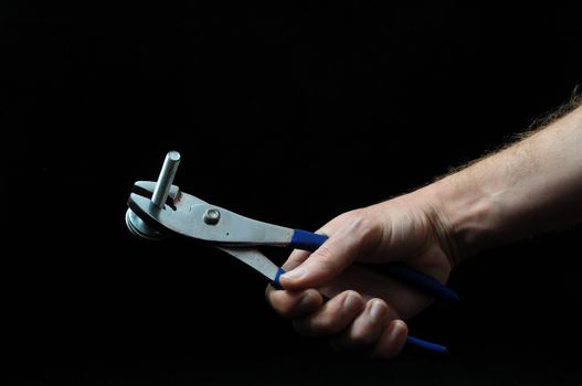 Pliers and a Hand on a Black Background