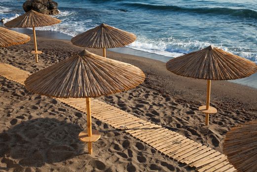 Dark sand beach with umbrellas on Crete, Greece 