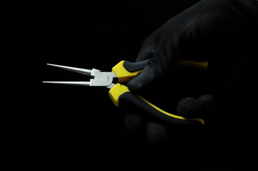 Pliers and a Hand on a Black Background