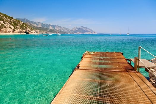 Pier at cove with clear turquoise water in Sardinia