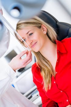 Optometry concept - pretty young woman having her eyes examined by an eye doctor (color toned image; shallow DOF)