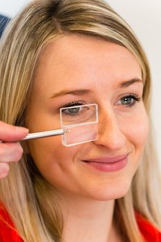 Optometry concept - pretty young woman having her eyes examined by an eye doctor (color toned image; shallow DOF)