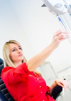 Optometry concept - pretty young woman having her eyes examined by an eye doctor (color toned image; shallow DOF)