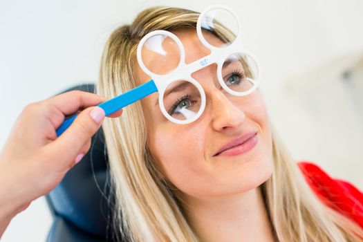 Optometry concept - pretty young woman having her eyes examined by an eye doctor (color toned image; shallow DOF)