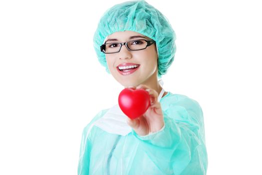 Smiling female doctor or nurse in surgical clothes holding red heart