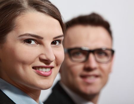 Portrait of a young smiling businesswoman with her colleague in the background, out of focus.