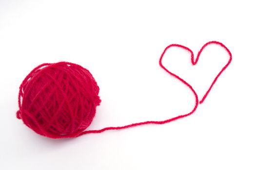 Red ball of wool creating a heart shape