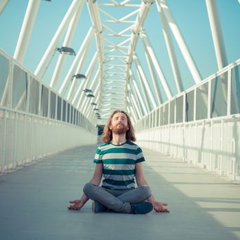 stylish hipster model with long red hair and beard yoga in the street