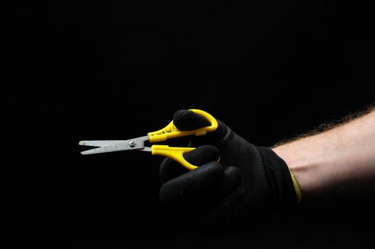 Scissors and a Hand on a Black Background