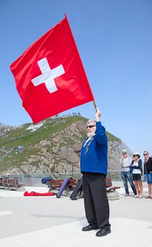 MOUNT PILATUS - JULY 13: Unidentified man demonstrating traditional swiss "flag throwing" on July 13, 2013 on the top of mount Pilatus, Switzerland. Flag twirling is one of the oldest national sports of Switzerland.