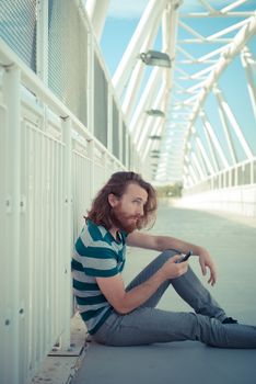 stylish hipster model with long red hair and beard lifestyle on the phone in the street