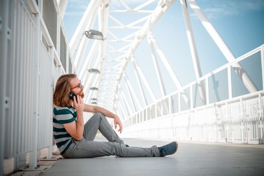 stylish hipster model with long red hair and beard lifestyle on the phone in the street